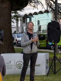 Guest speaker Dr Peggy Eby has shoulder-length ash-coloured hair and is wearing a grey jacket and dark coloured pants as she is talking to the crowd.